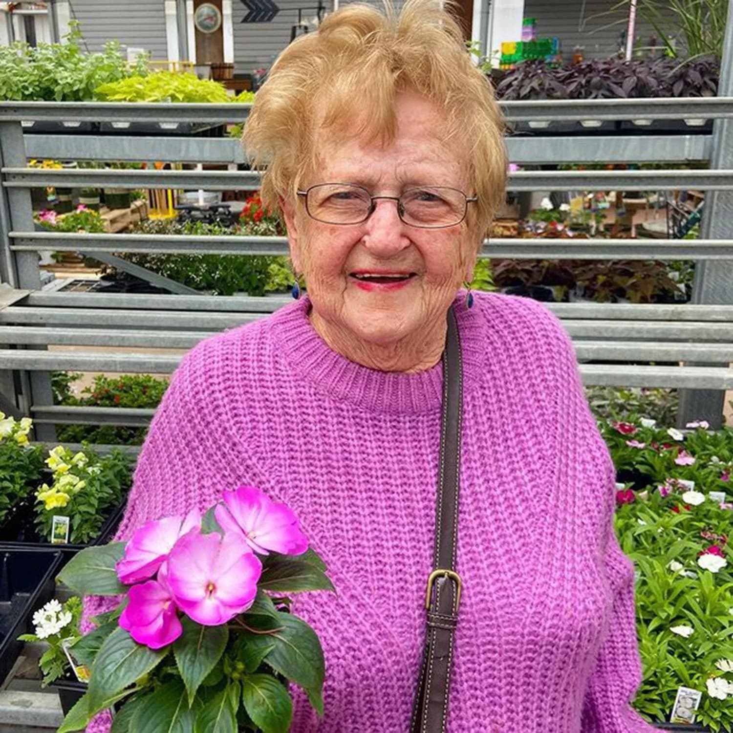 Lillian Droniak holds a bright pink impatiens flower.
