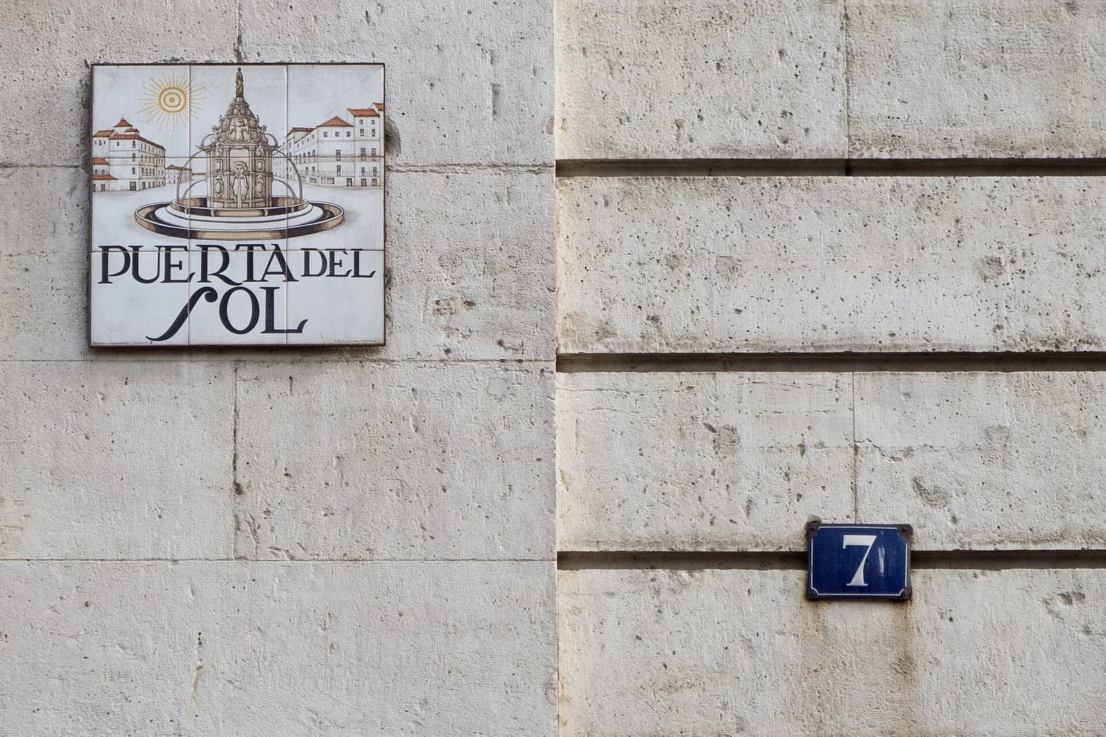 Ceramic ‘Puerta del Sol’ street sign on a stone wall in Madrid.