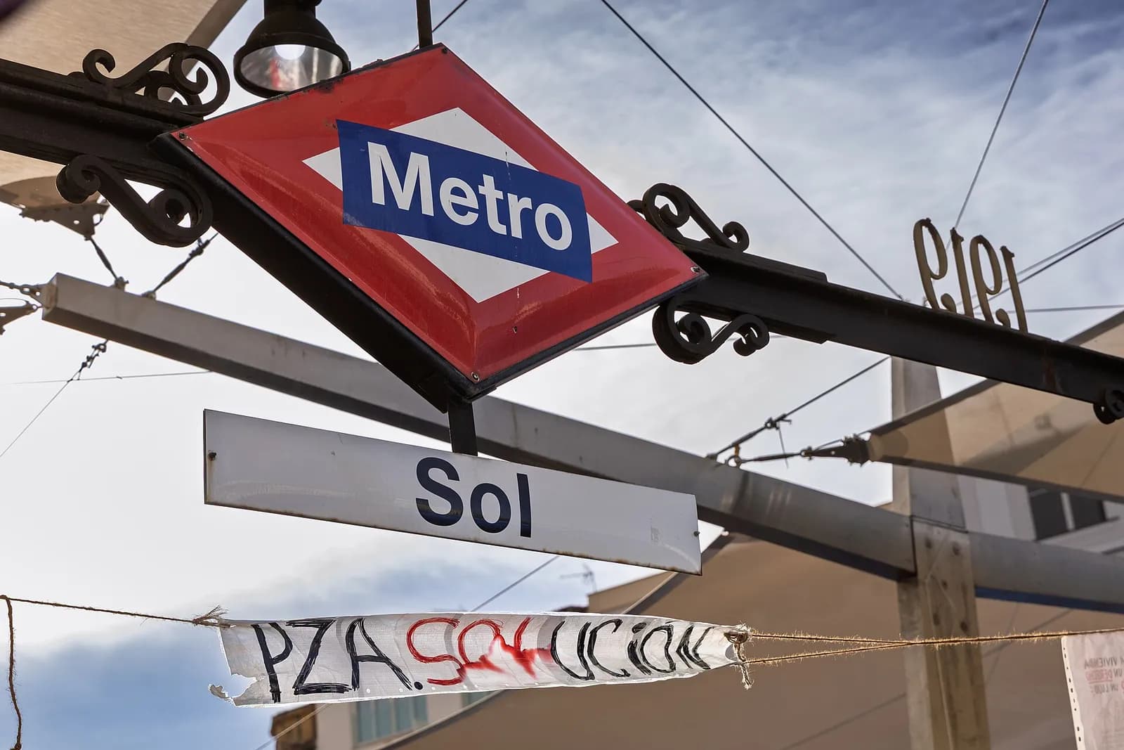 A weathered banner hangs above the entrance to Sol metro station in Puerta del Sol, Madrid.