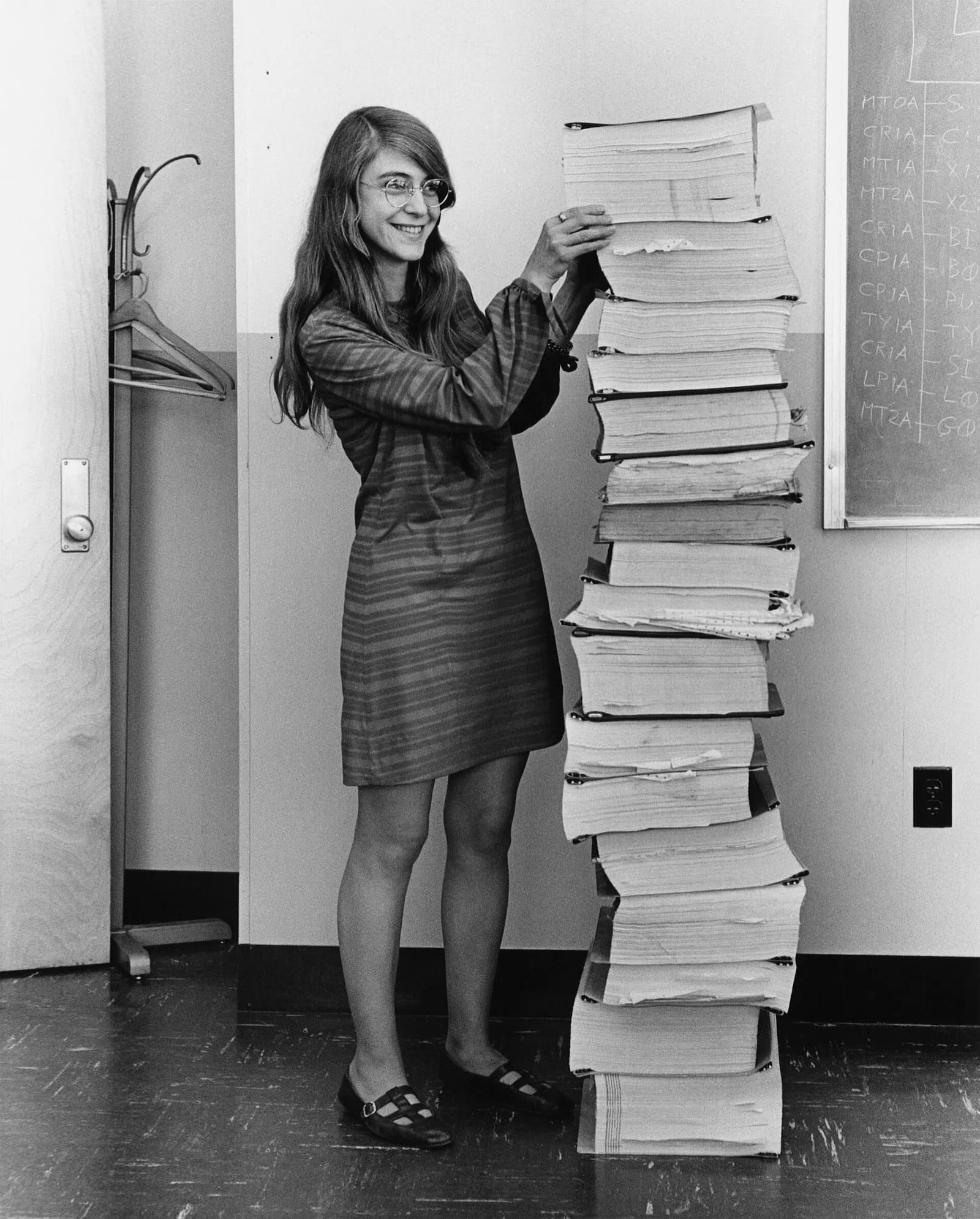 Margaret Hamilton standing beside printed listings of Apollo flight software developed by her and her MIT team.