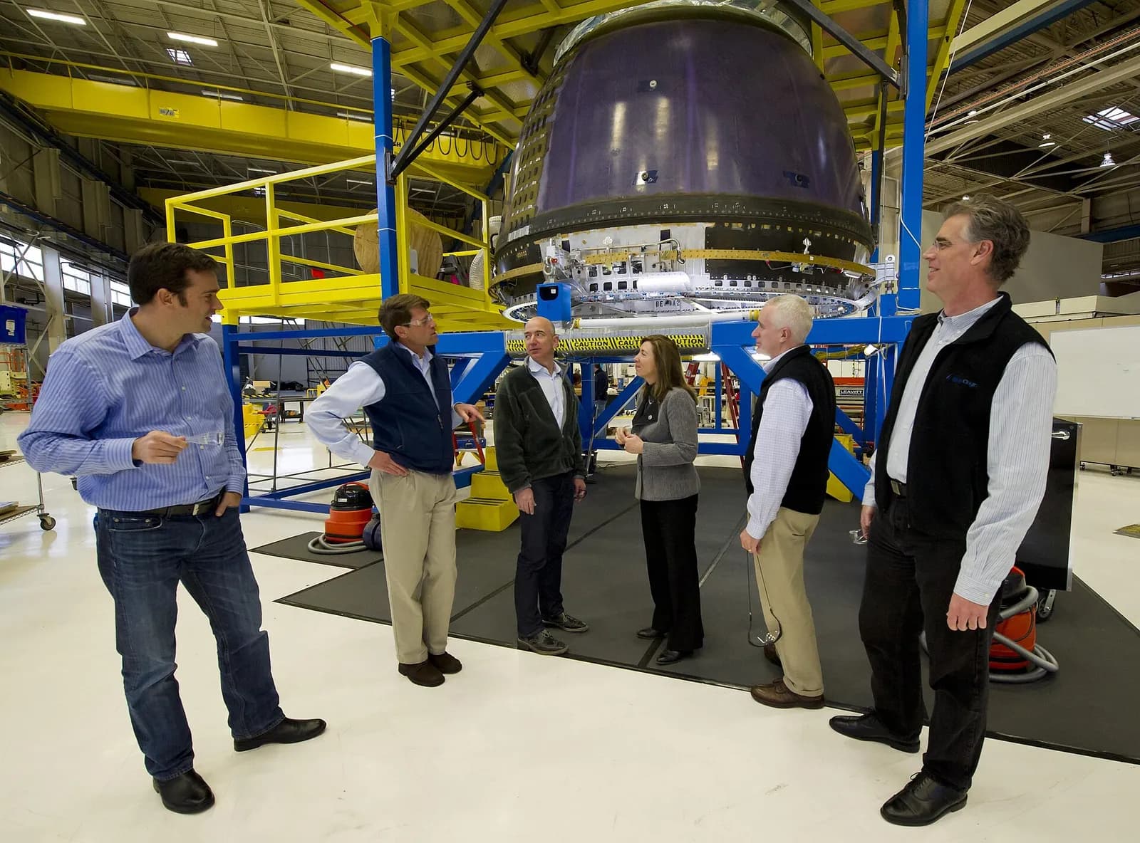 Jeff Bezos and Blue Origin team members stand beside a crew capsule at the company’s headquarters.