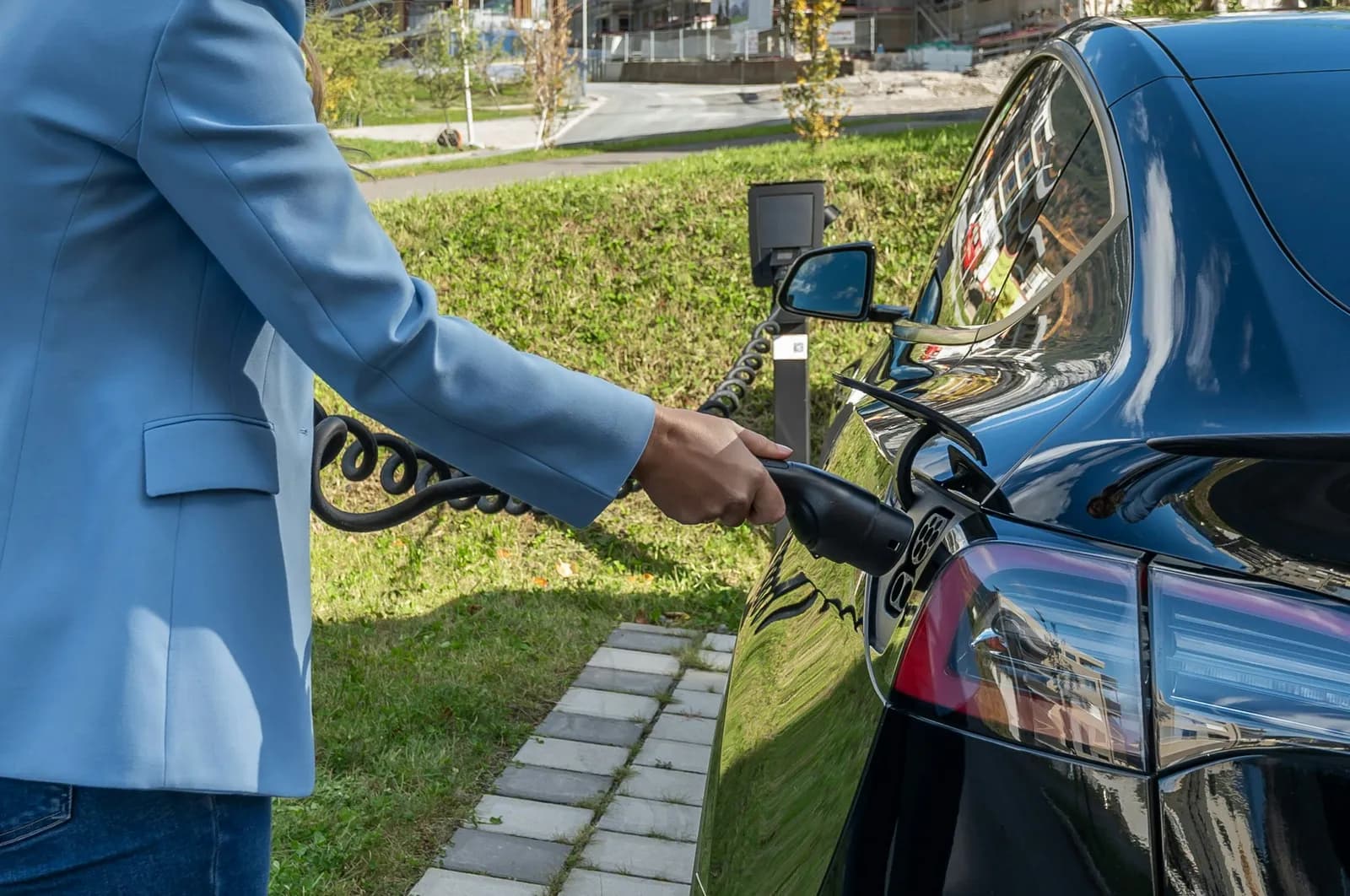 A person connects an electric car to a charging station.