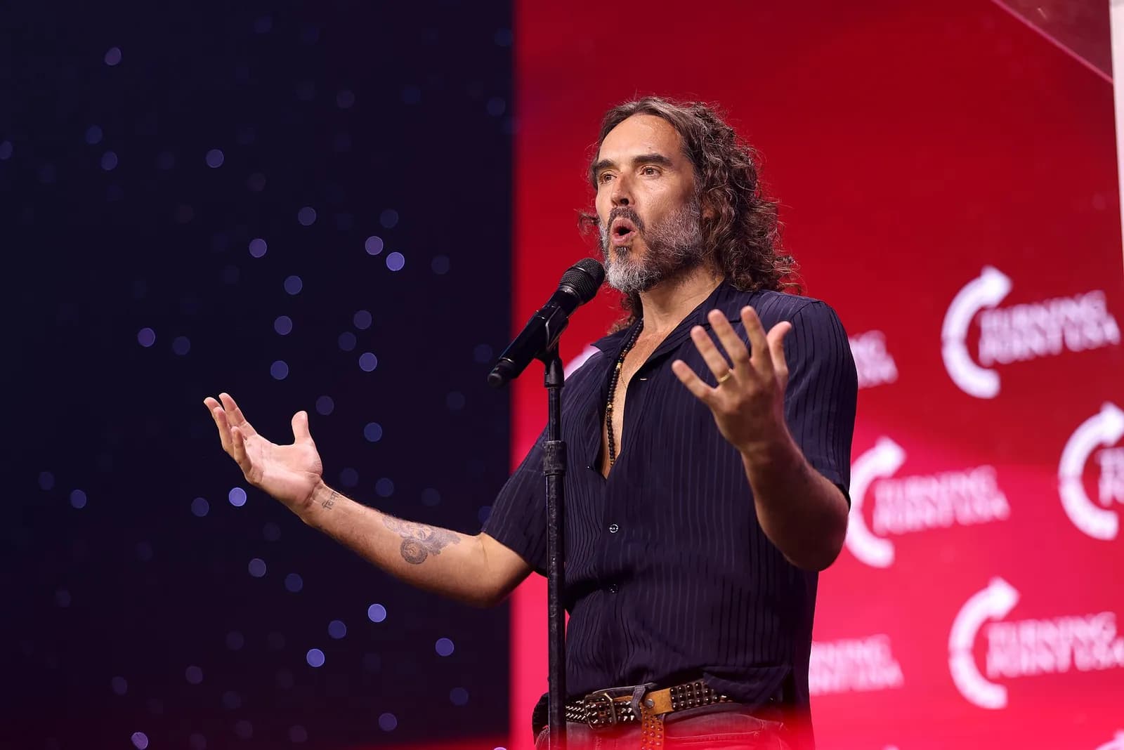Russell Brand speaking with attendees at the 2025 Student Action Summit in Tampa, Florida.