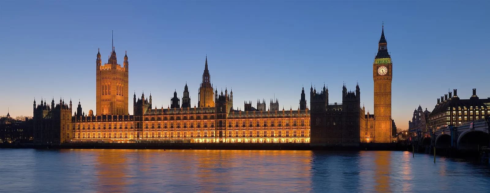 The Palace of Westminster, with the Elizabeth Tower and Victoria Tower, viewed across the River Thames at dusk.