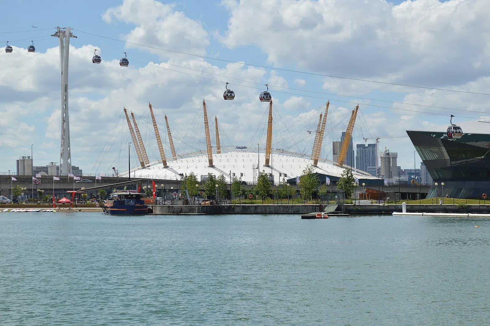 The O2 venue in Greenwich, London, with cable cars and an Emirates Air Line support tower visible.