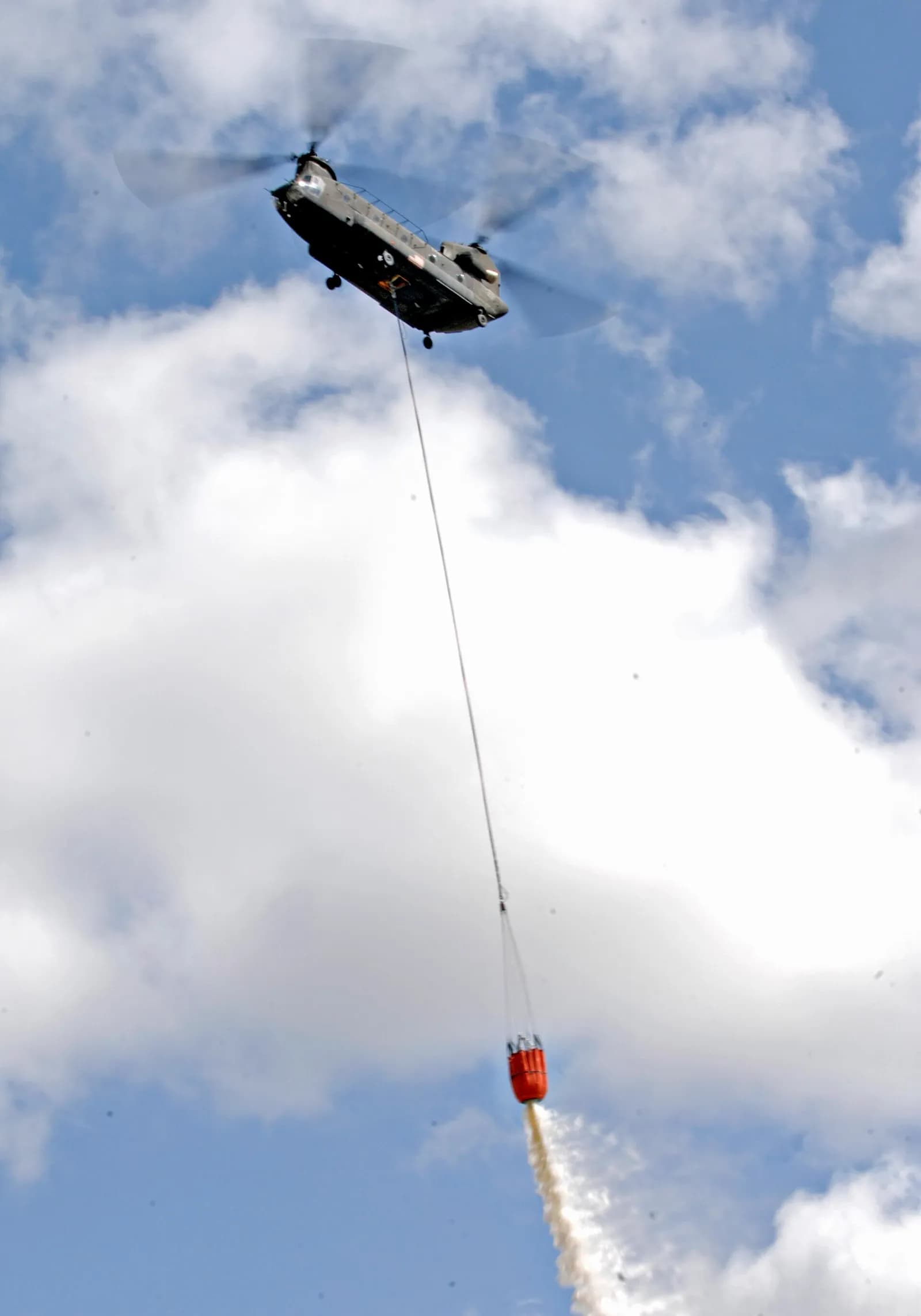 An Oregon Army National Guard CH-47 Chinook helicopter demonstrates aerial firefighting with a water bucket.