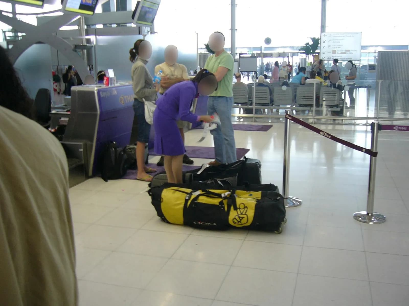 A Thai Airways employee attaches a baggage tag to a passenger’s suitcase at the check-in counter.