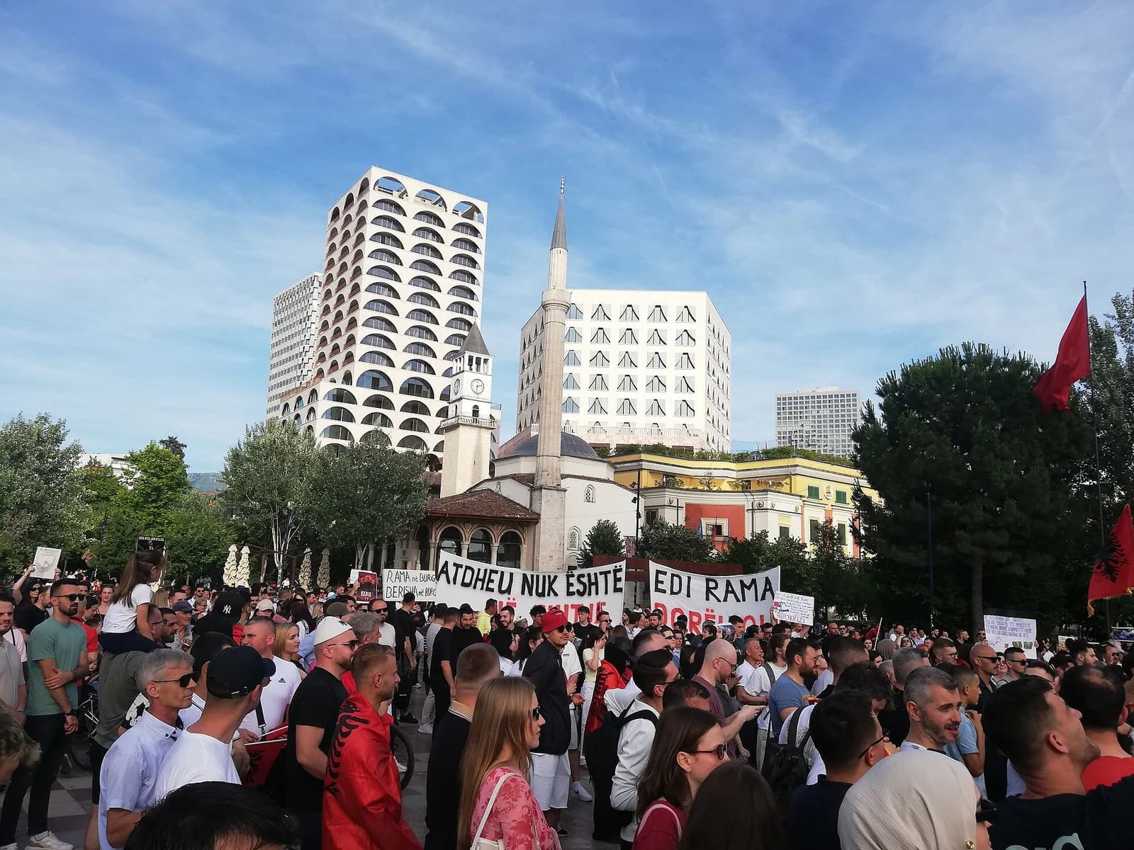 Crowds carrying banners and Albanian flags during a protest in Tirana’s Skanderbeg Square in June 2026.