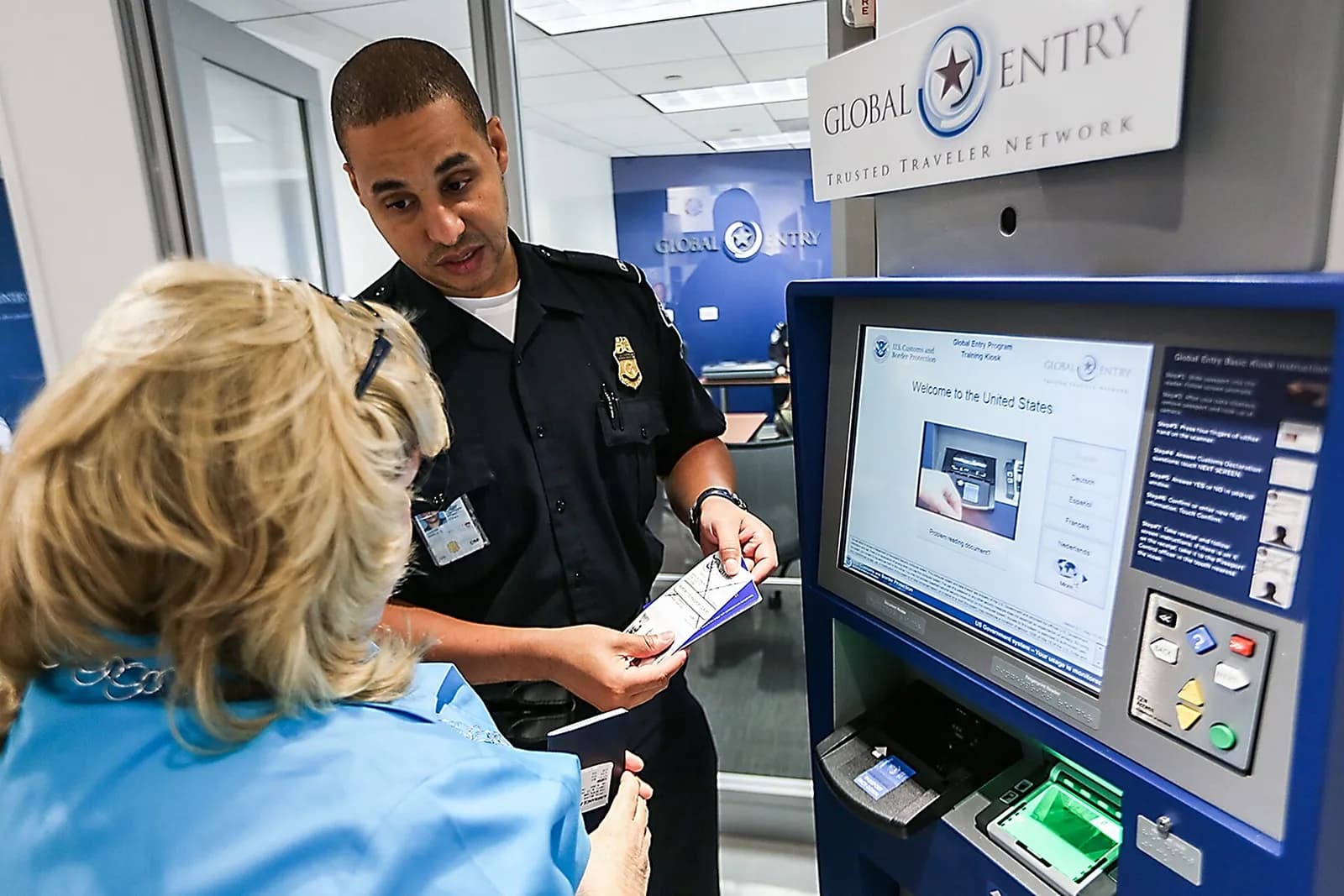 A CBP officer trains an enrollee at a Global Entry kiosk.