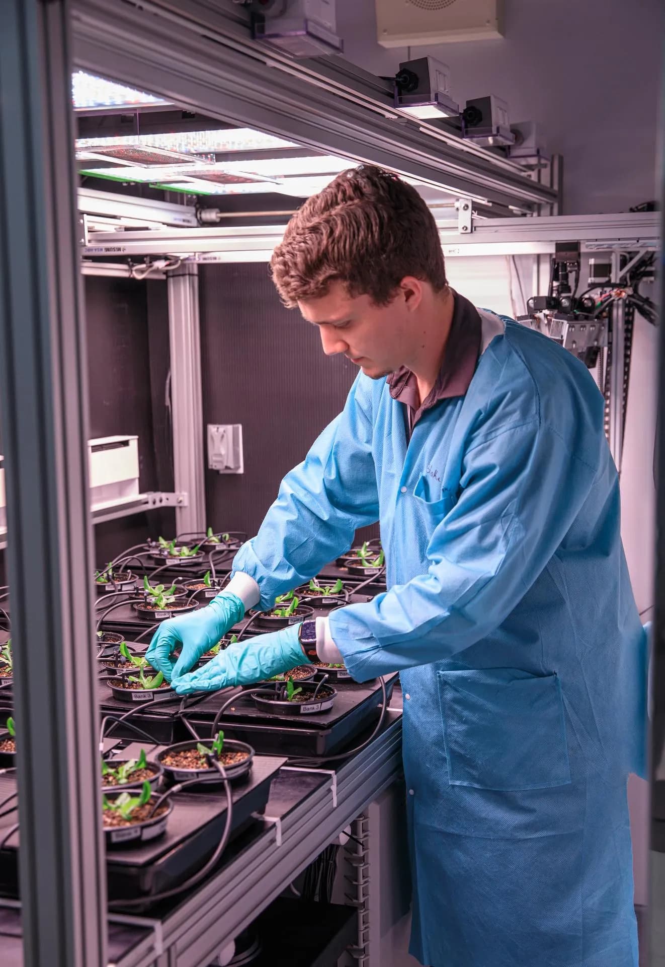 Horticulture scientist Blake Costine adjusts moisture sensors in a plant production area at NASA’s Kennedy Space Center.