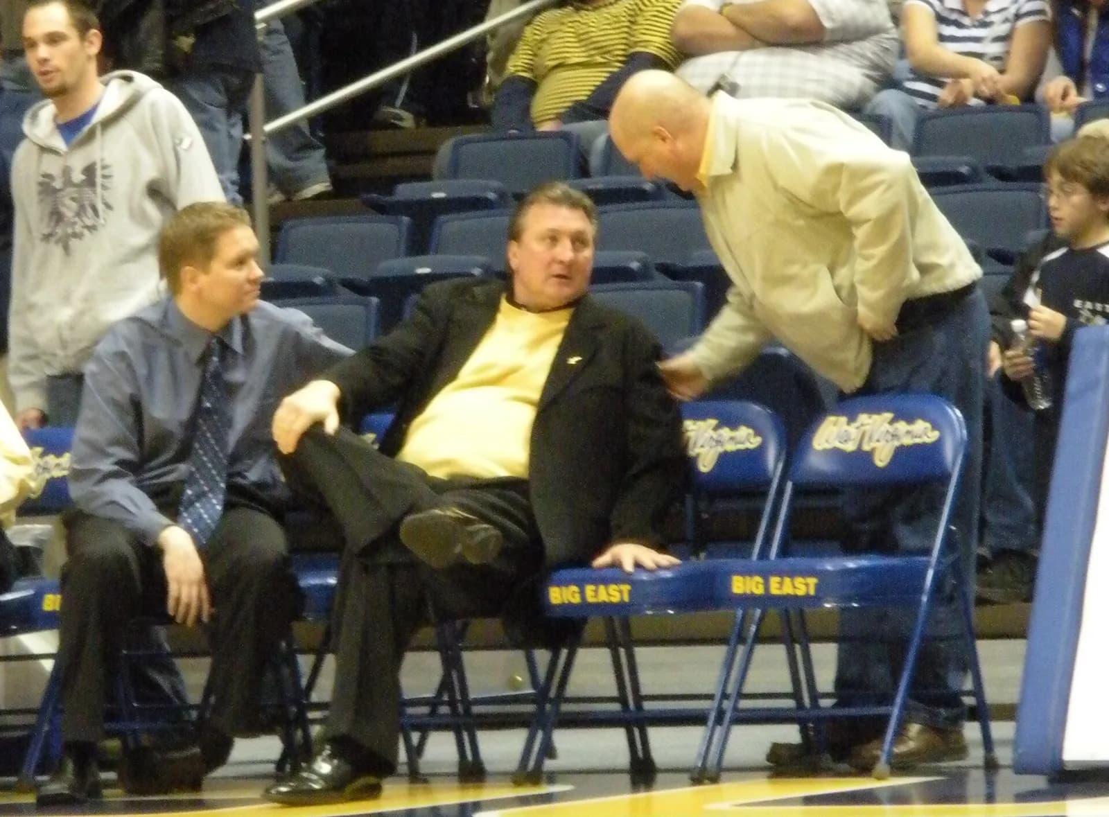 Bob Huggins sits on the sideline during a West Virginia Mountaineers home basketball game.