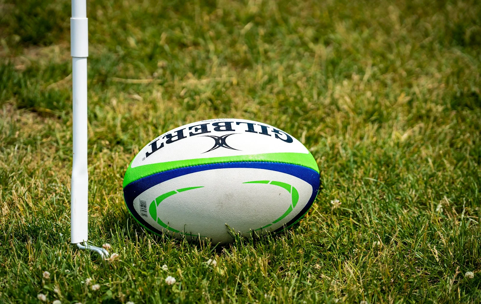 A rugby ball on grass near a corner flag